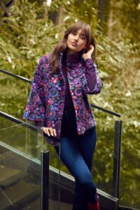 A woman wearing a multi-coloured patterned long-sleeved jacket. 